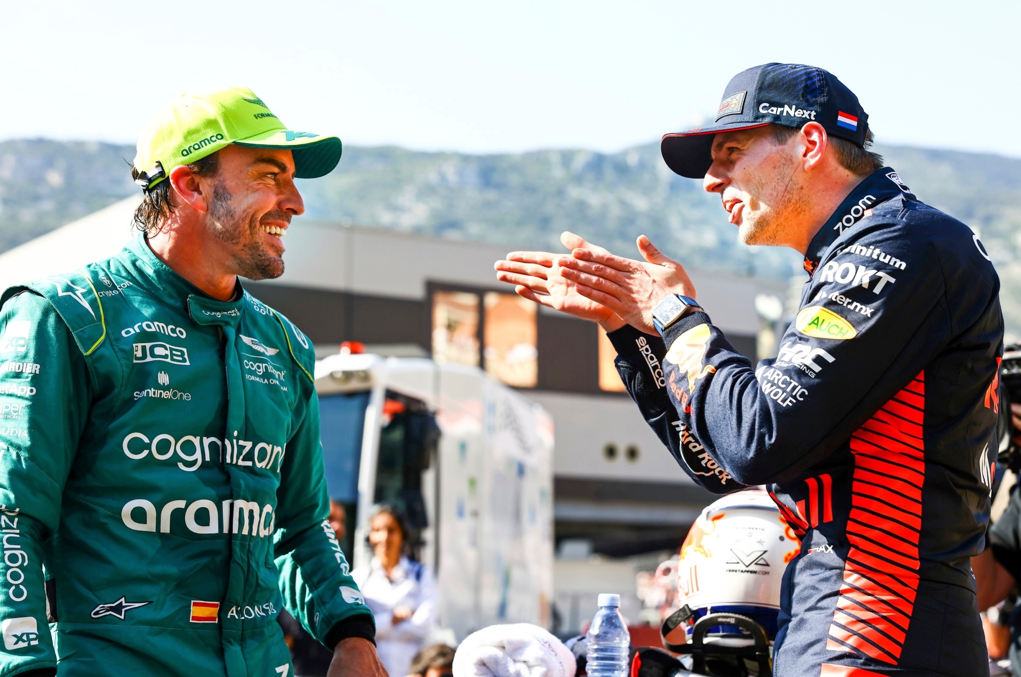 Alonso y Verstappen sonríen mientras dialogan.